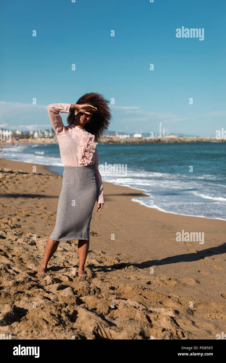 Young woman with afro hairdo standing on the beach Stock Photo