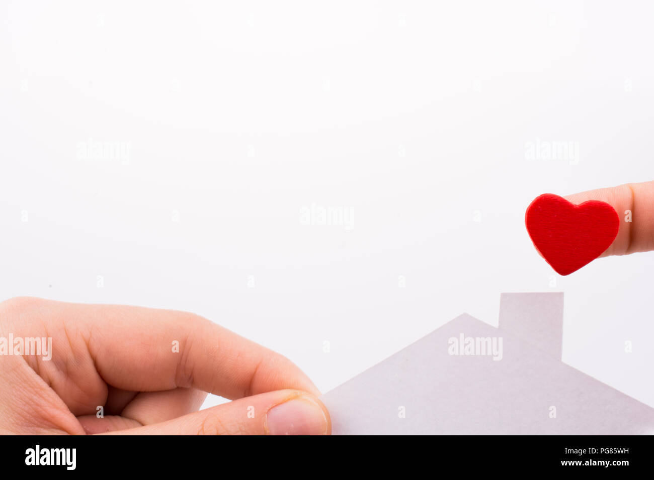 Paper house and heart shape in hand on a white background Stock Photo ...