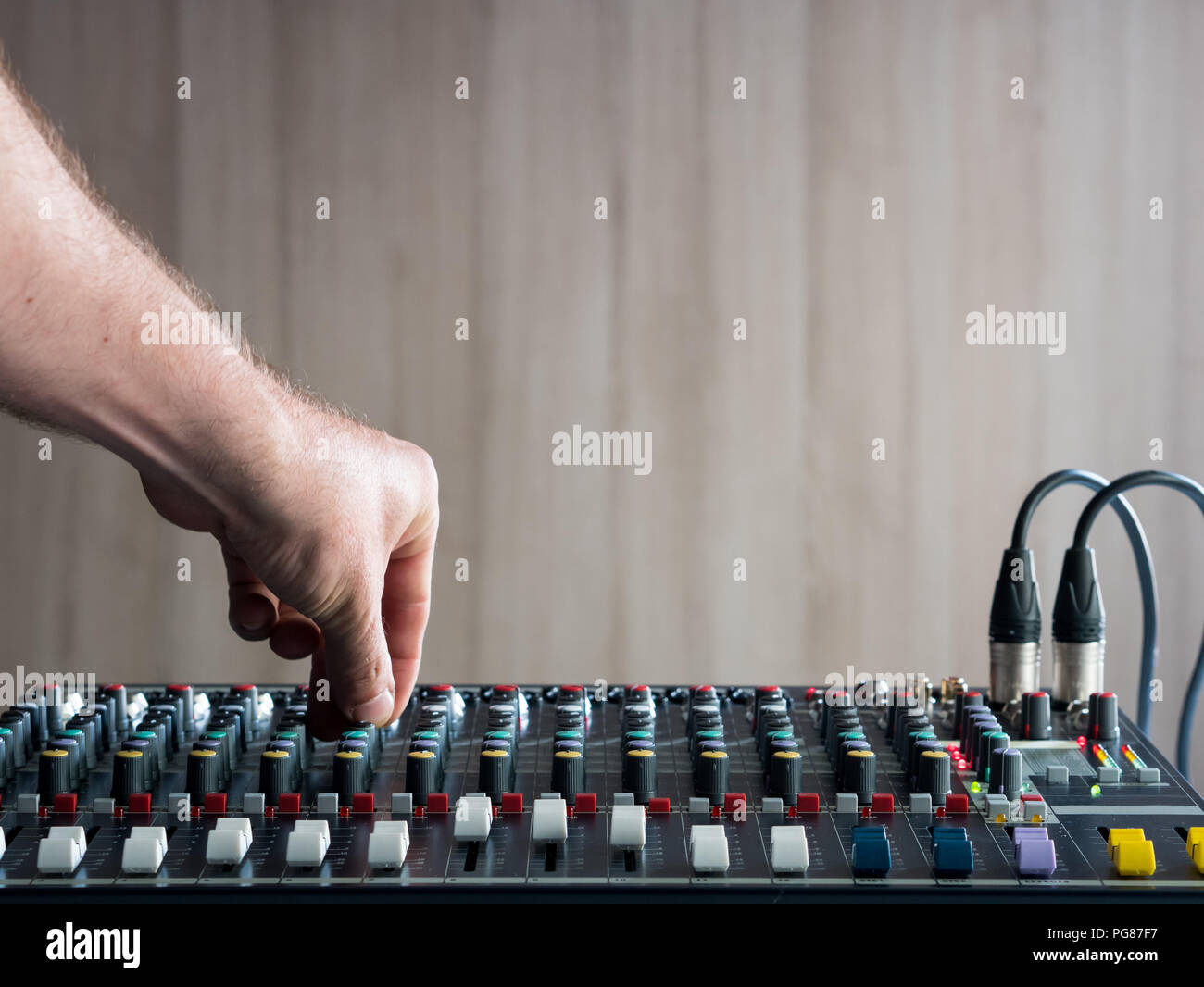 Mans hand adjusting buttons on audio mixer in music studio Stock Photo
