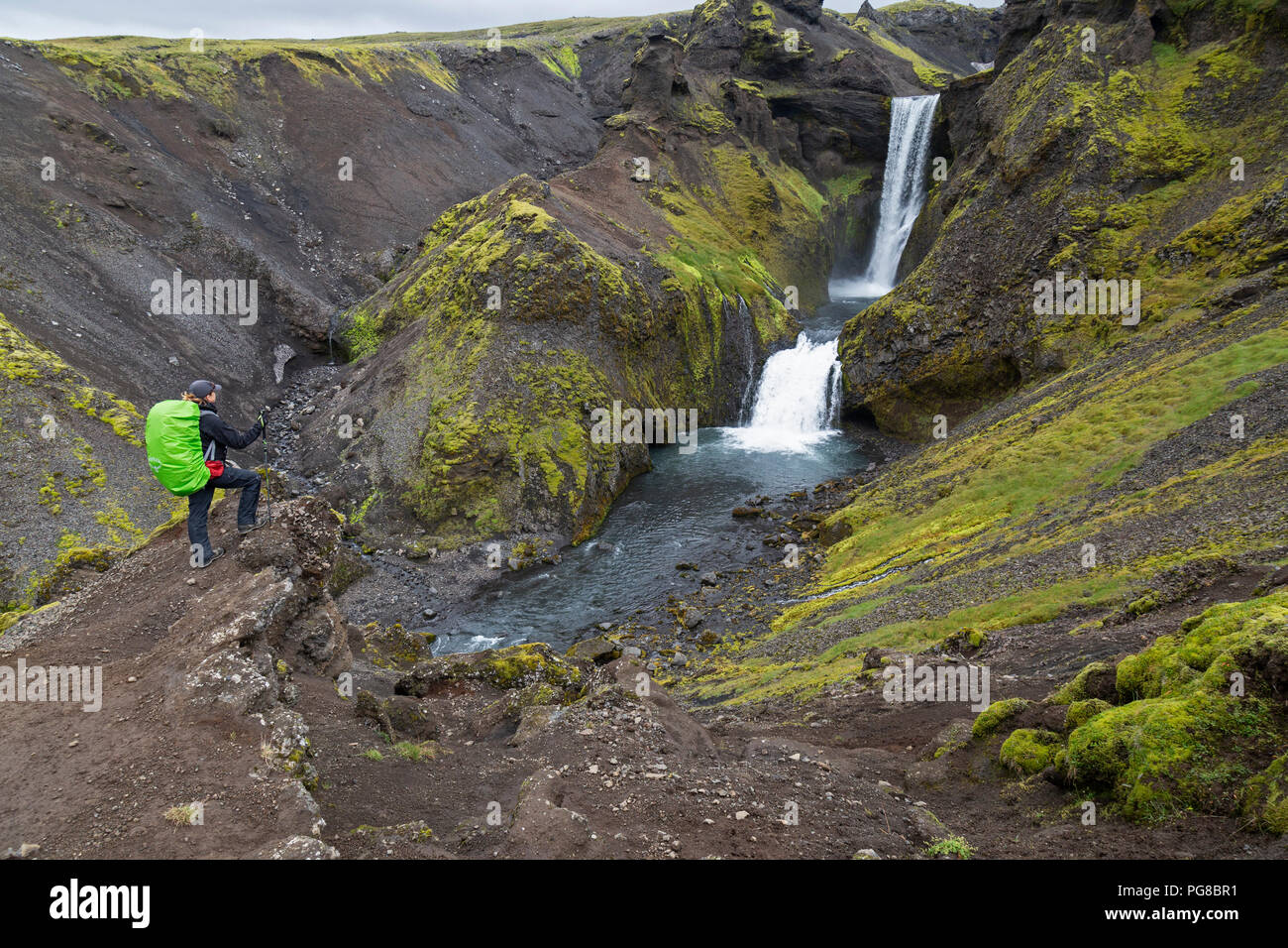 A lone female tourist looks over a waterfall in Iceland, on part of the Laugavegur trail. Stock Photo