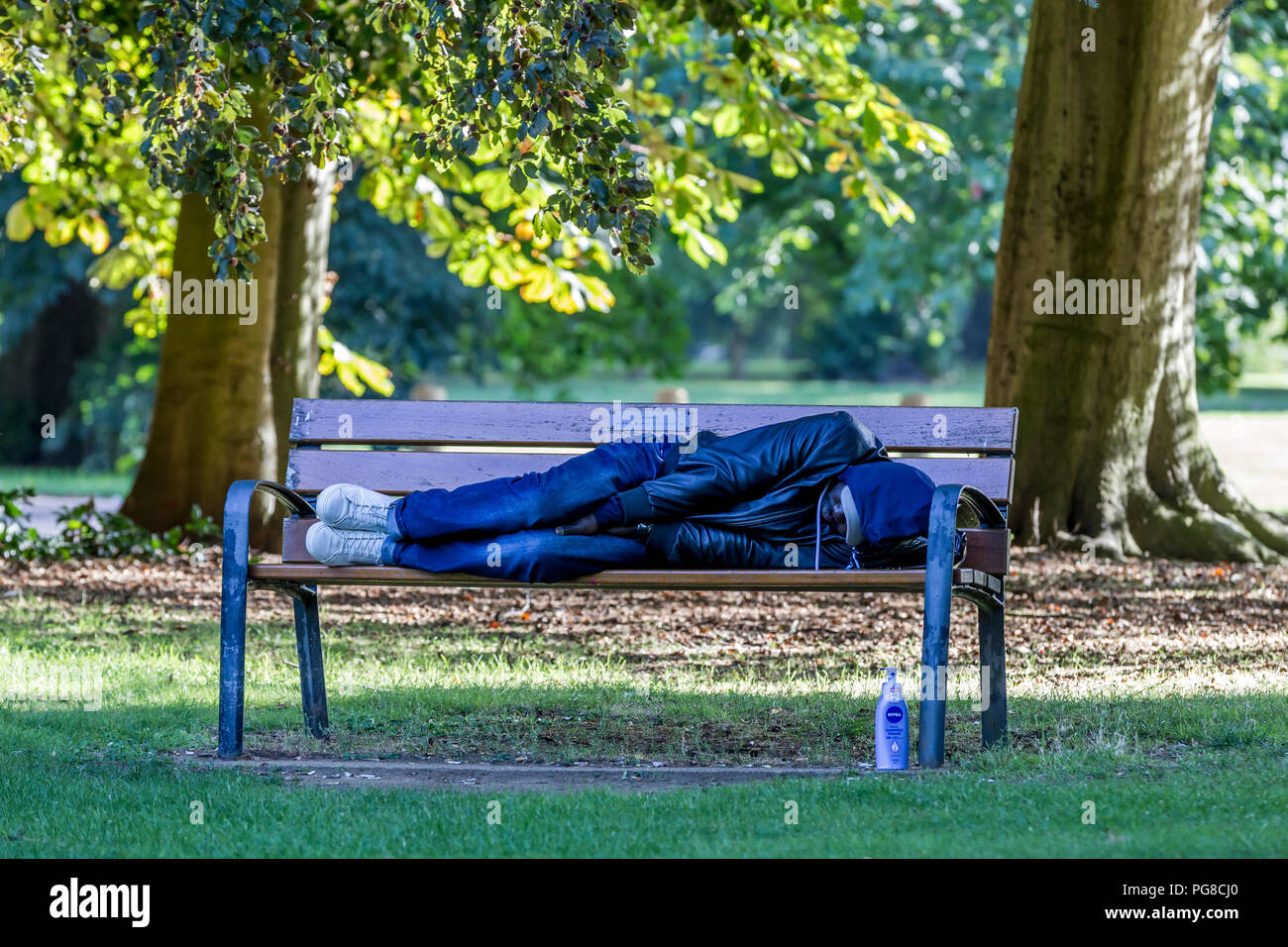 Northampton. U.K. 24th August 2018.  A man sleeping it off or sleeping rough on a park bench in Abington Park this morning, homeless people use the benches and bus shelters around the town park, temperatures were in single figures last night making it feel much colder than of late. Credit: Keith J Smith./Alamy Live News Stock Photo
