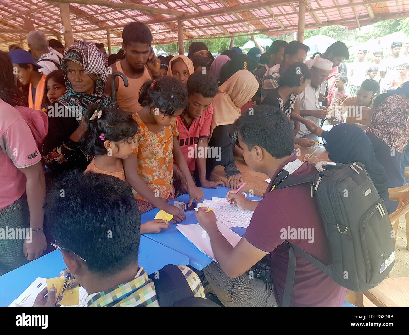 13 August 2018, Bangladesh, Cox's Bazar: Residents of a Rohingya refugee camp collect stamps for the allocation of fuel rods from compressed rice husks for cooking by the aid organization FIVDB, a Bangladeshi partner of Welthungerhilfe. Photo: Nick Kaiser/dpa Stock Photo