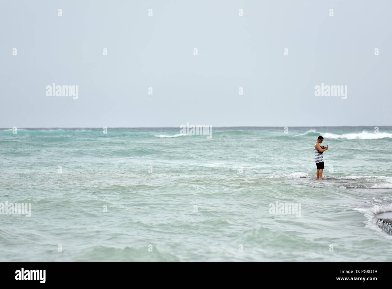 Honolulu, USA. 23rd Aug, 2018. A man takes pictures on the seawall at Waikiki beach in Honolulu of Hawaii, the United States, Aug. 23, 2018. Hurricane Lane, predicted as the biggest weather threat to Hawaii in decades, moved perilously close to the Aloha State Thursday morning, triggering heavy rain, landslide and flooding. Credit: Sun Ruibo/Xinhua/Alamy Live News Stock Photo