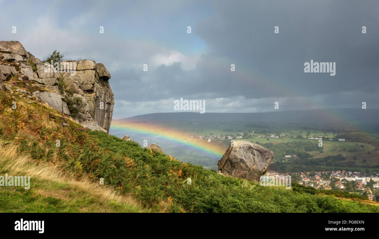 UK weather: Cow and Calf Rocks, Ilkley Moor, West Yorkshire, UK. 24th August 2018. Double rainbow links the Cow with the Calf on a day of sunshine and heavy rain.  Rebecca Cole/Alamy Live News Stock Photo