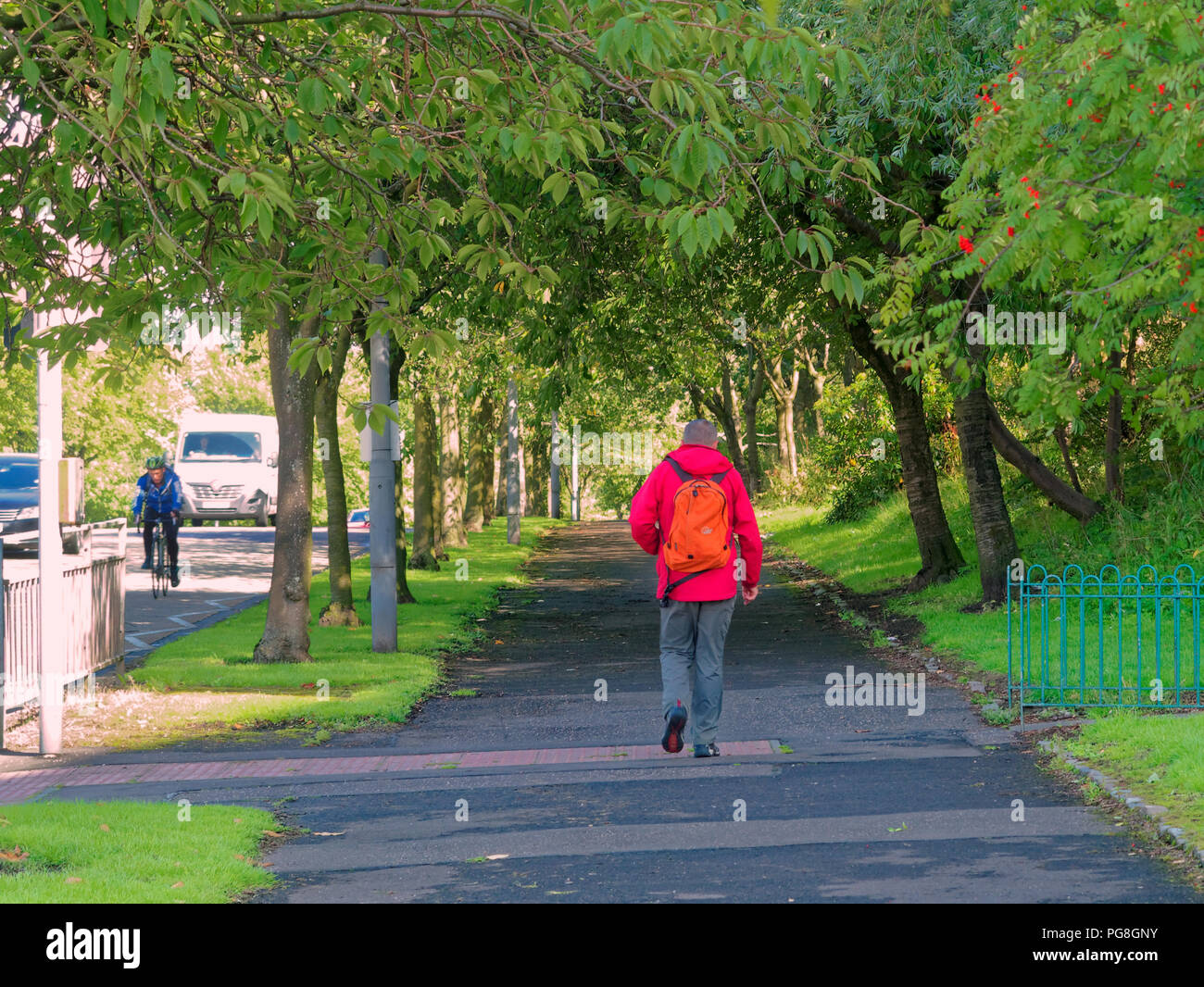 Glasgow, Scotland, UK. 24th Aug, 2018. UK Weather: Brighter weather sees locals unsure of rain or shine as life goes on as someone walks down the avenue of trees on great western road towards the city dressed for the great outdoors as a cyclist travels down the A82 the gateway to the western highlands. Credit: gerard ferry/Alamy Live News Stock Photo