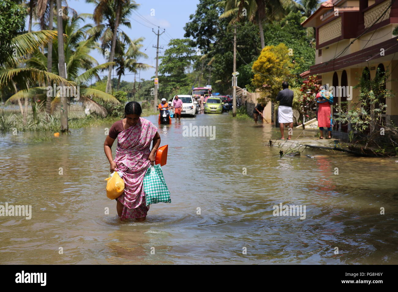 Kerala. 22nd Aug, 2018. People wade through flood water in India's southernmost flood-hit Kerala state, Aug. 22, 2018. According to media reports, the death toll in the devastating floods has reached 370. Credit: Zhao Xu/Xinhua/Alamy Live News Stock Photo