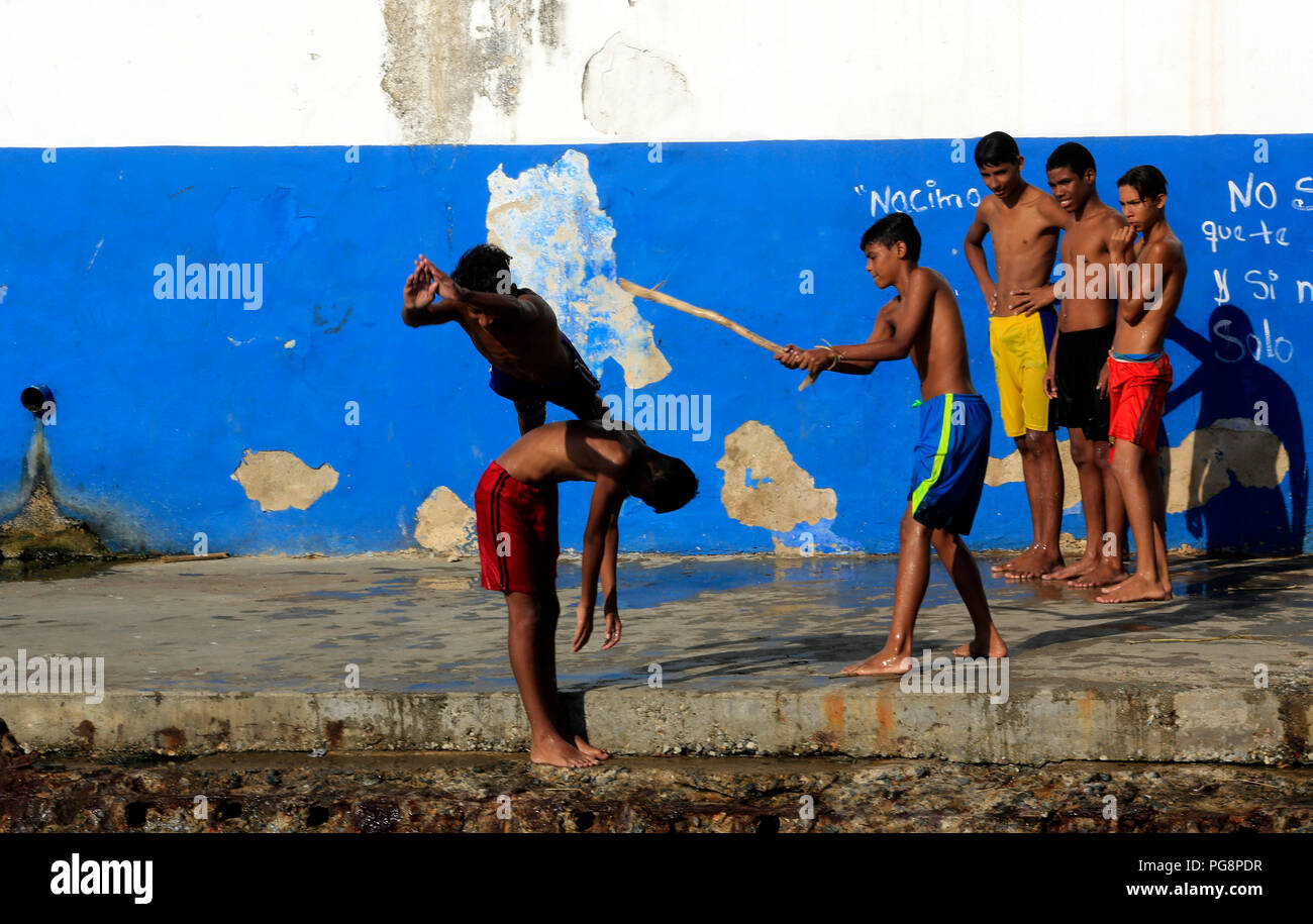 Puerto Cabello, Carabobo, Venezuela. 24th Aug, 2018. August 24, 2018. Young residents play games that end up in the sea, in the malecon of Puerto Cabello, Carabobo state. Photo: Juan Carlos Hernandez Credit: Juan Carlos Hernandez/ZUMA Wire/Alamy Live News Stock Photo