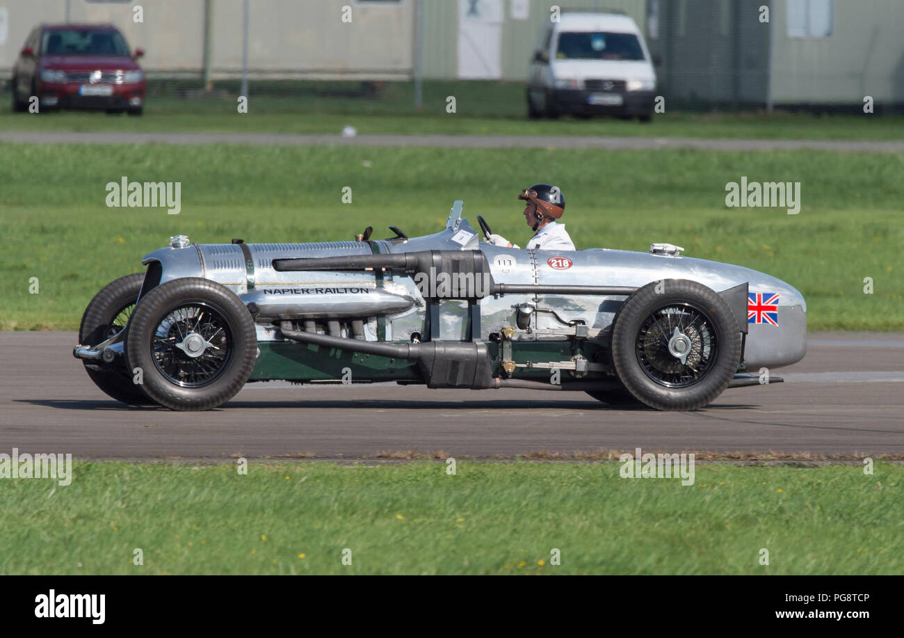 Dunsfold Park, Surrey, UK. 25 August, 2018. Weekend iconic aviation and motoring show at Dunsfold features the RAF Red Arrows, Battle of Britain Memorial Flight, Mitchell bomber, RAF Typhoon and modern, classic & vintage supercars plus music and dance. Photo: The iconic Brooklands Museum 24 litre Napier-Railton passes at high speed on the runway, this car is the holder in perpetuity of the lap record at the famous Brookland Circuit. Credit: Malcolm Park/Alamy Live News. Stock Photo