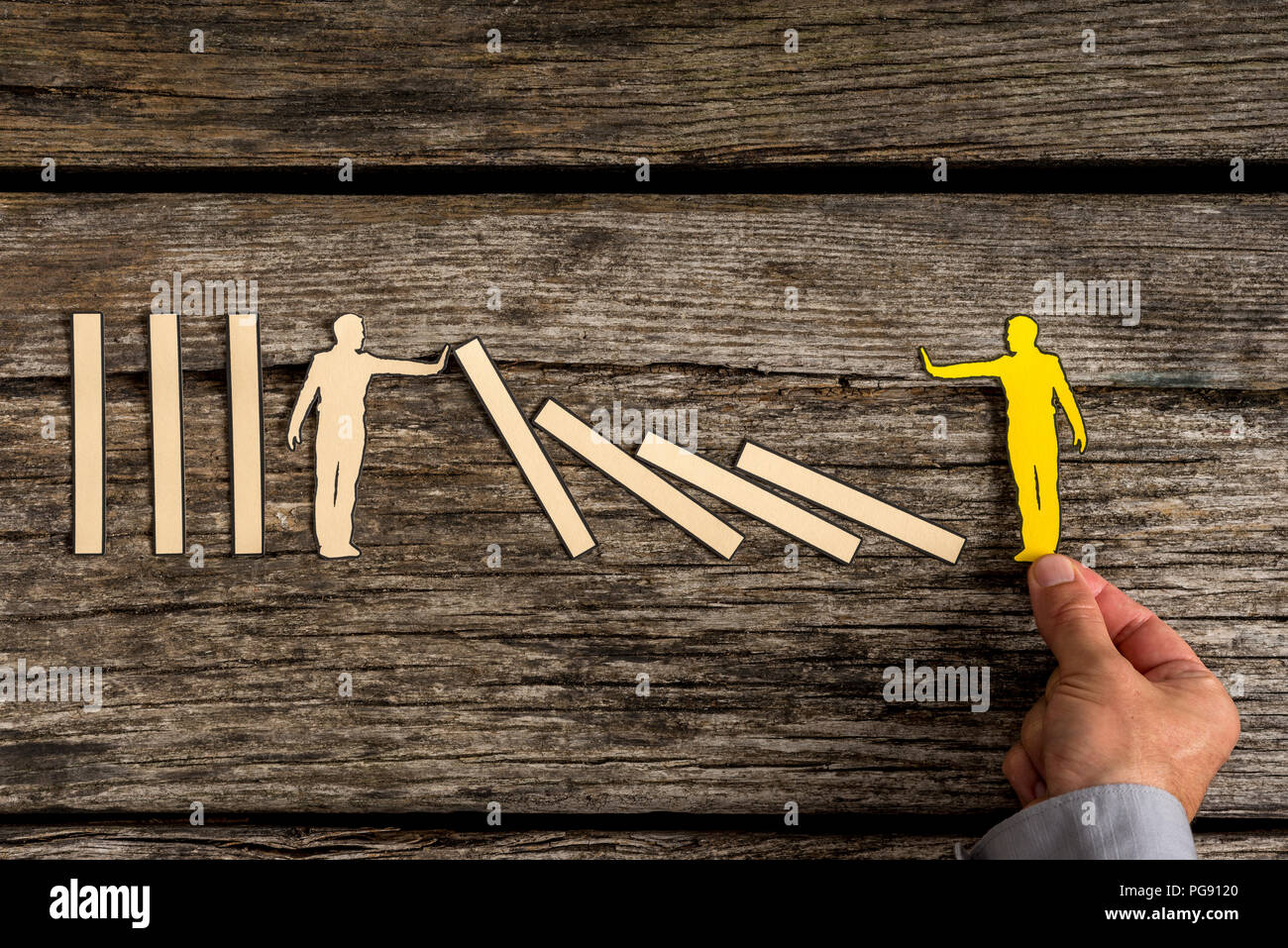 Silhouette cutout of a man holding up fallen blocks as yellow small person  pushes dominoes down Stock Photo - Alamy