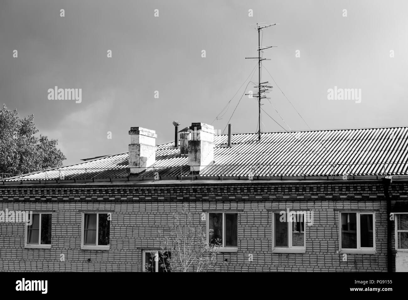 Black and white photo of chimneys and television aerial on the roof of apartment house against cloudy sky. Komsomolsk-on-Amure, Russia Stock Photo