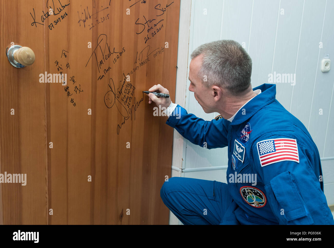 Expedition 55 flight engineer Drew Feustel of NASA performs the traditional door signing at the Cosmonaut Hotel prior to departing the hotel for launch on a Soyuz rocket with fellow crewmates Oleg Artemyev of Roscosmos and Ricky Arnold of NASA, Wednesday, March 21, 2018 in Baikonur, Kazakhstan.  Feustel, Artemyev, and Arnold will launch in their Soyuz MS-08 spacecraft to the International Space Station to being a five month mission. Stock Photo