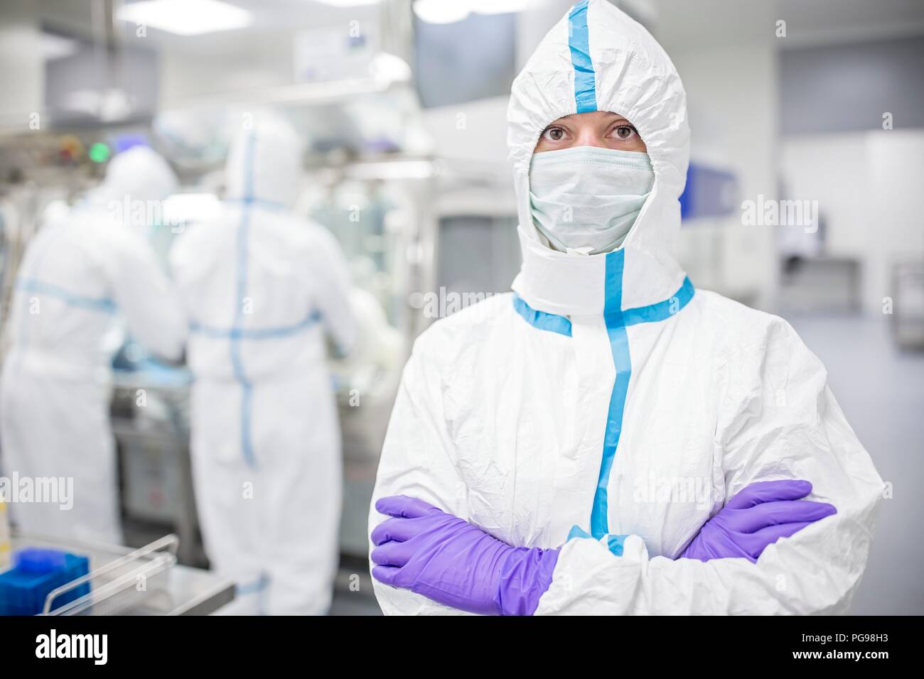 Lab technician wearing a protective suit and face mask in a laboratory that must maintain a sterile environment. Stock Photo