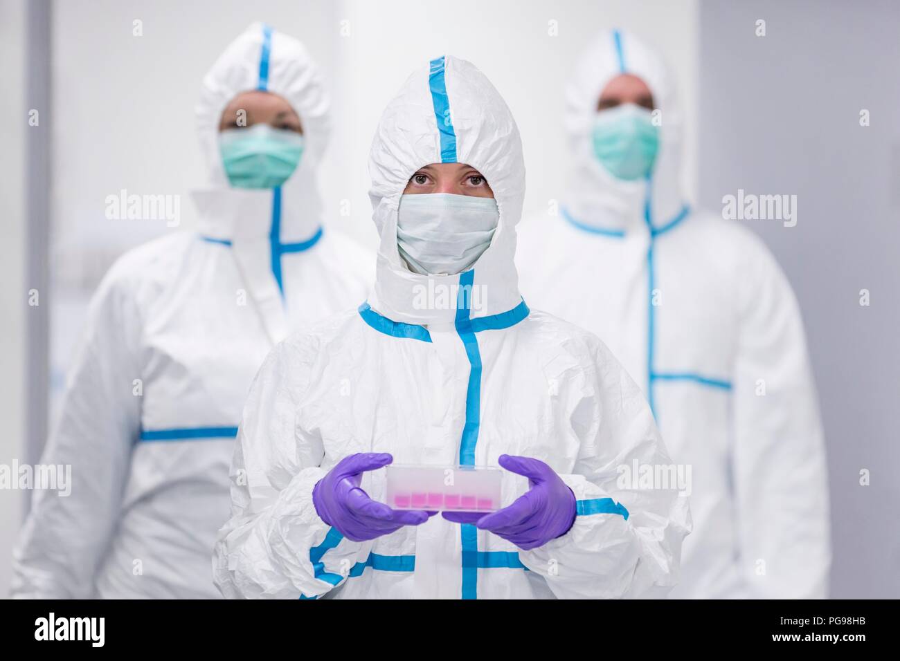 Lab technician carrying a cell-based testing kit in a laboratory that engineers human tissues for implant. Such implants include bone and skin grafts. Stock Photo