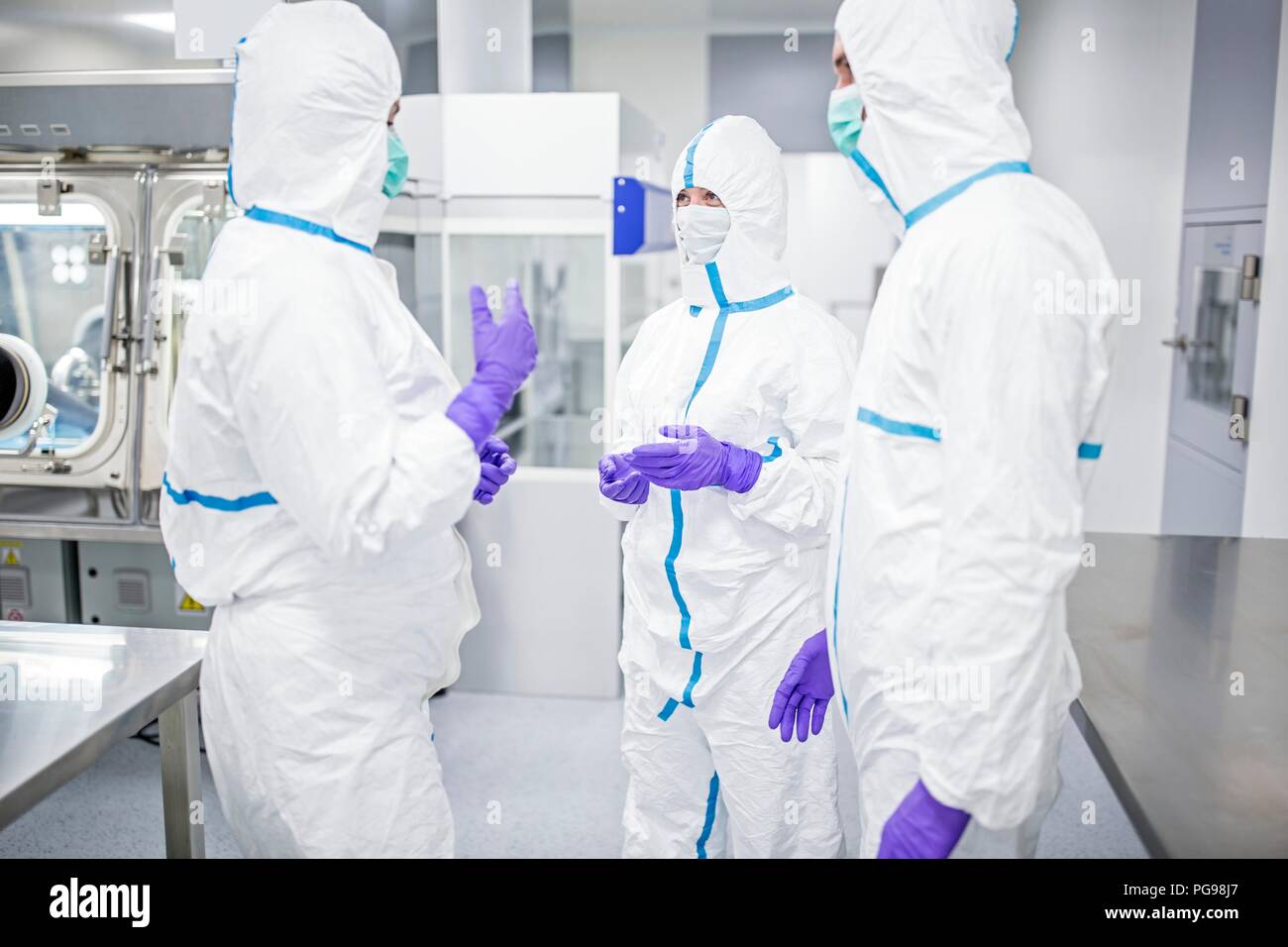 Lab technicians wearing protective suits and face masks in a laboratory that must maintain a sterile environment. Stock Photo