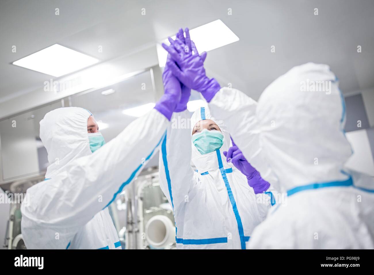 Lab technicians in a sterile environment high-fiving. Stock Photo