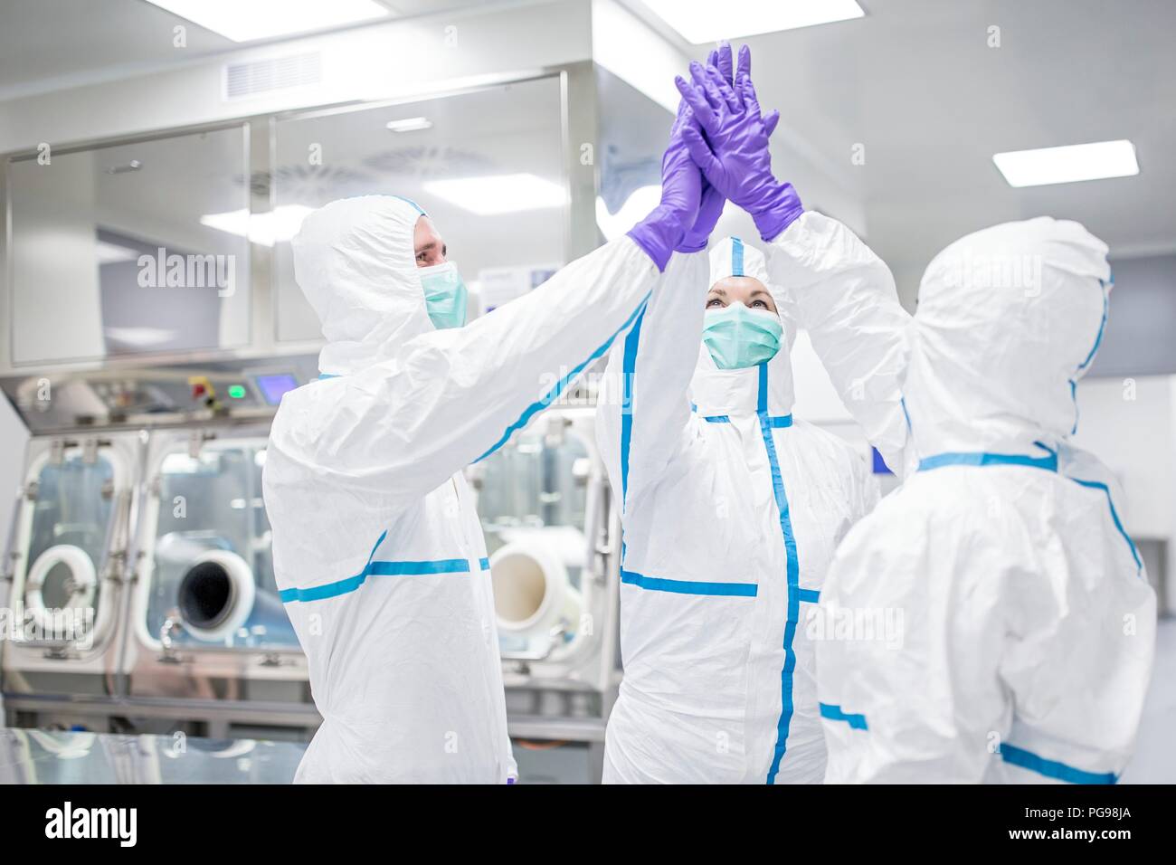 Lab technicians in a sterile environment high-fiving. Stock Photo