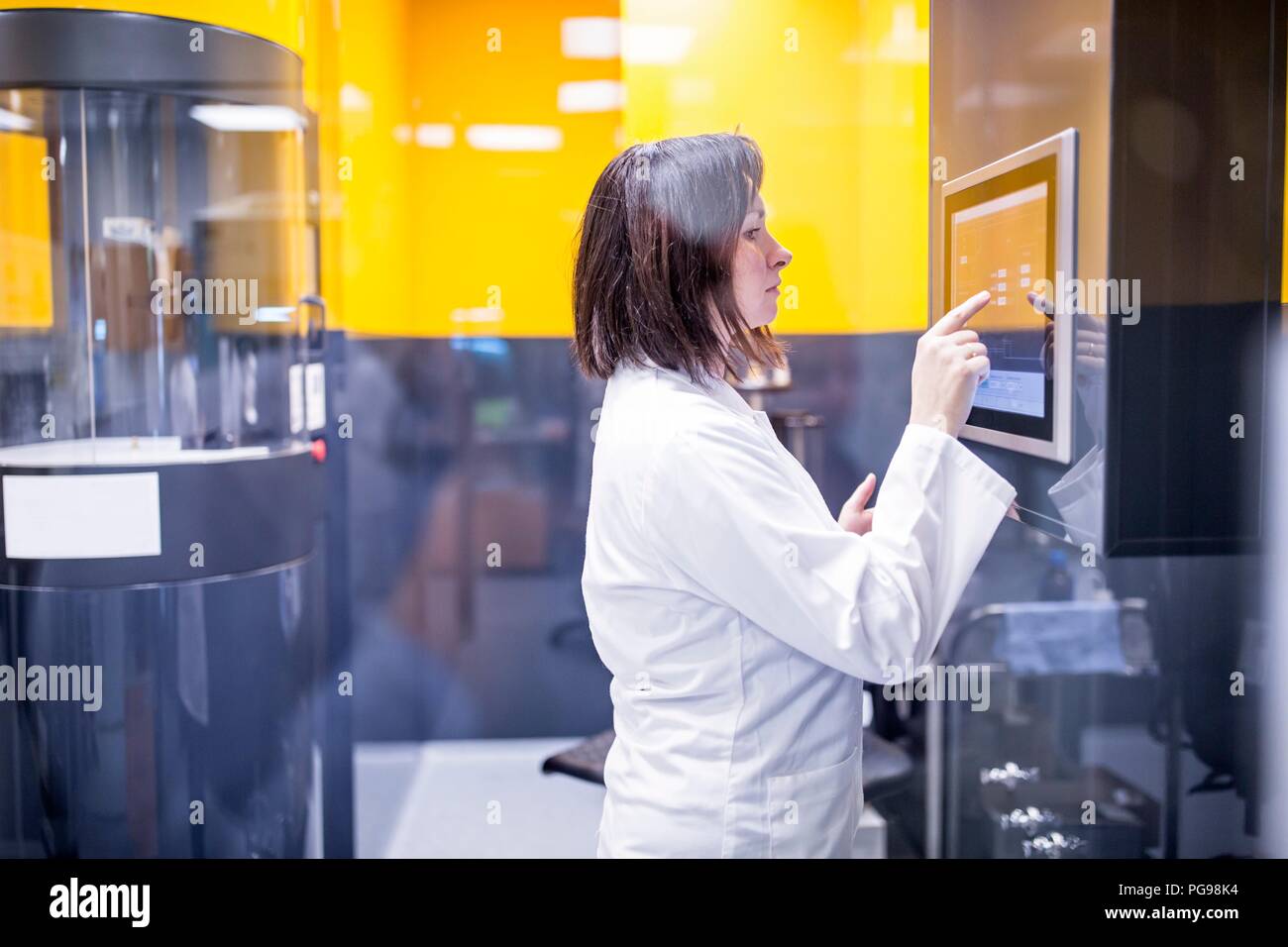Technician programming a machine in a nanofibre laboratory. This lab is using nanofibres to manufacture biodegradable materials for tissue scaffolds. Stock Photo