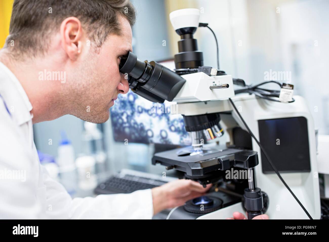 Scientist checking a nanofibre structure under a light microscope. Stock Photo