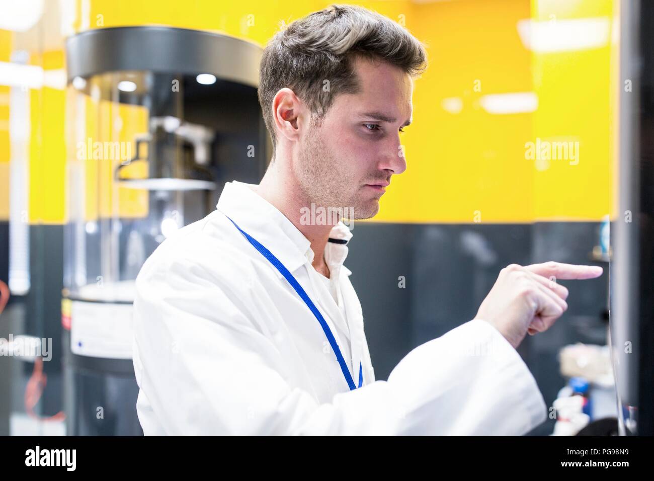 Technician in a nanofibre laboratory. An electrospinning machine is in the background. This lab is using nanofibres to manufacture biodegradable materials for tissue scaffolds. Stock Photo