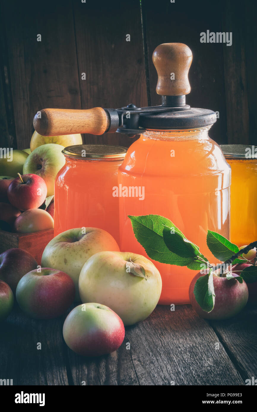 Glass jars of apple juice, apple fruits and can lid closing machine for