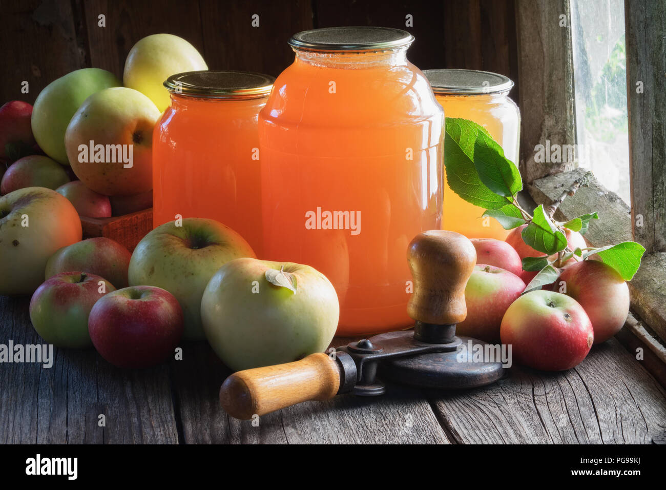 Glass jars of apple juice, apple fruits and can lid closing machine for