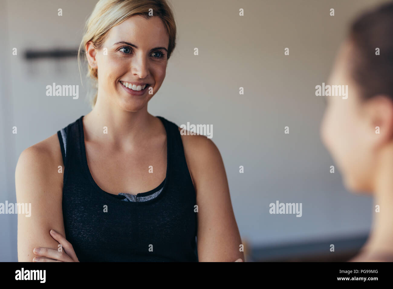 Smiling woman in fitness wear at a pilates training gym. Woman talking to a friend at the gym. Stock Photo