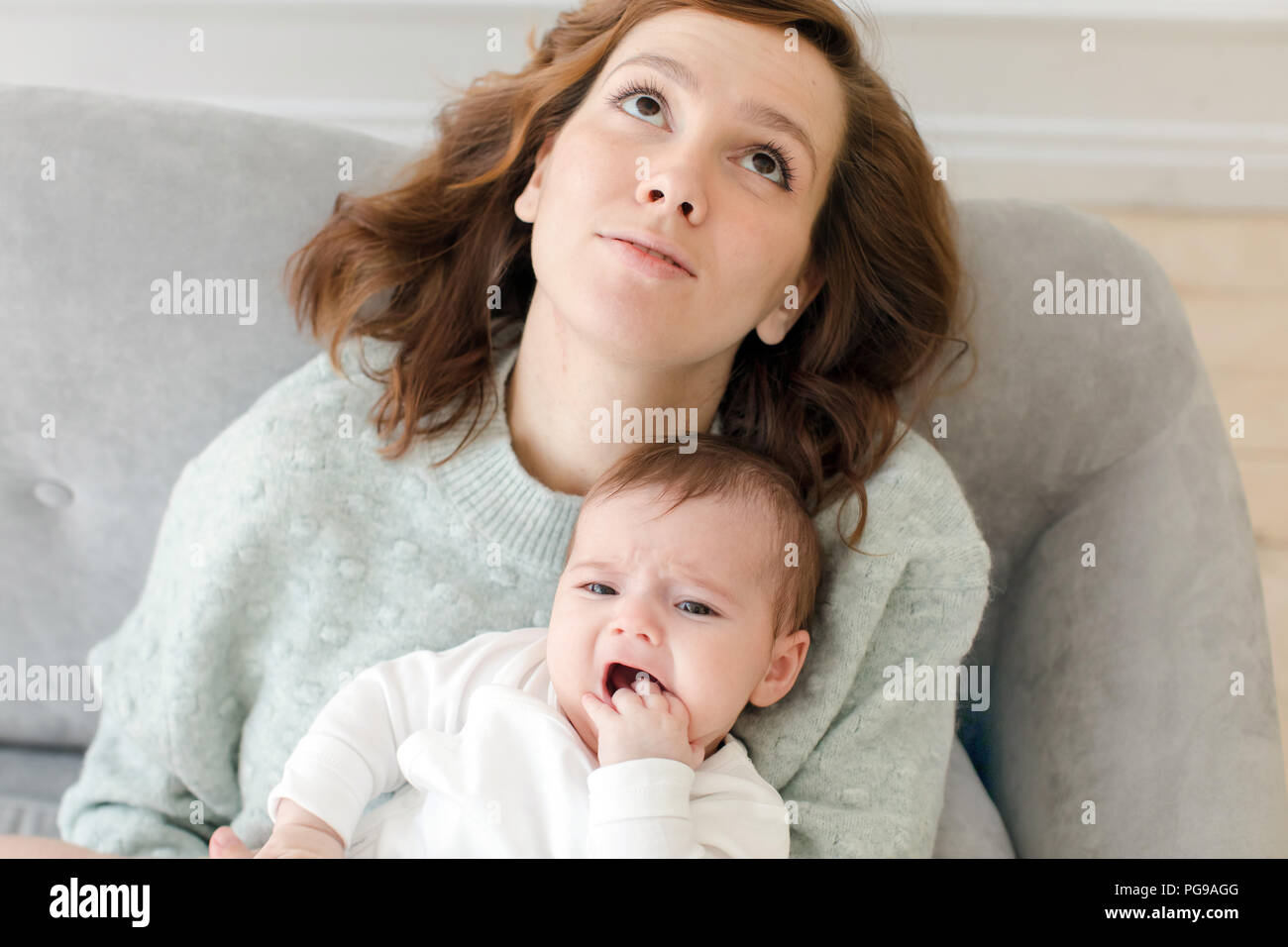 Young mother holding baby on knees and looking up Stock Photo