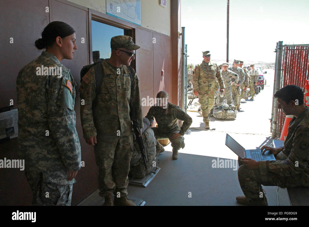 Spc. Kristine Kennedy (left), Spc. Hannah Beck (center right), and Pvt. Juan Pastrana (right), all members of the 213th Personnel Company, 213th Regional Support Group, Pennsylvania Army National Guard, weigh Staff Sgt. Jeremy Churchill (center left), an Alpha Company, 1st Battalion, 110th Infantry Regiment, 56th Stryker Brigade Combat Team, 28th Infantry Division infantryman, and his luggage during out-processing at the National Training Center, Fort Irwin, California Aug. 23. (U.S. Army National Guard photo by Sgt. Shane Smith/released) Stock Photo