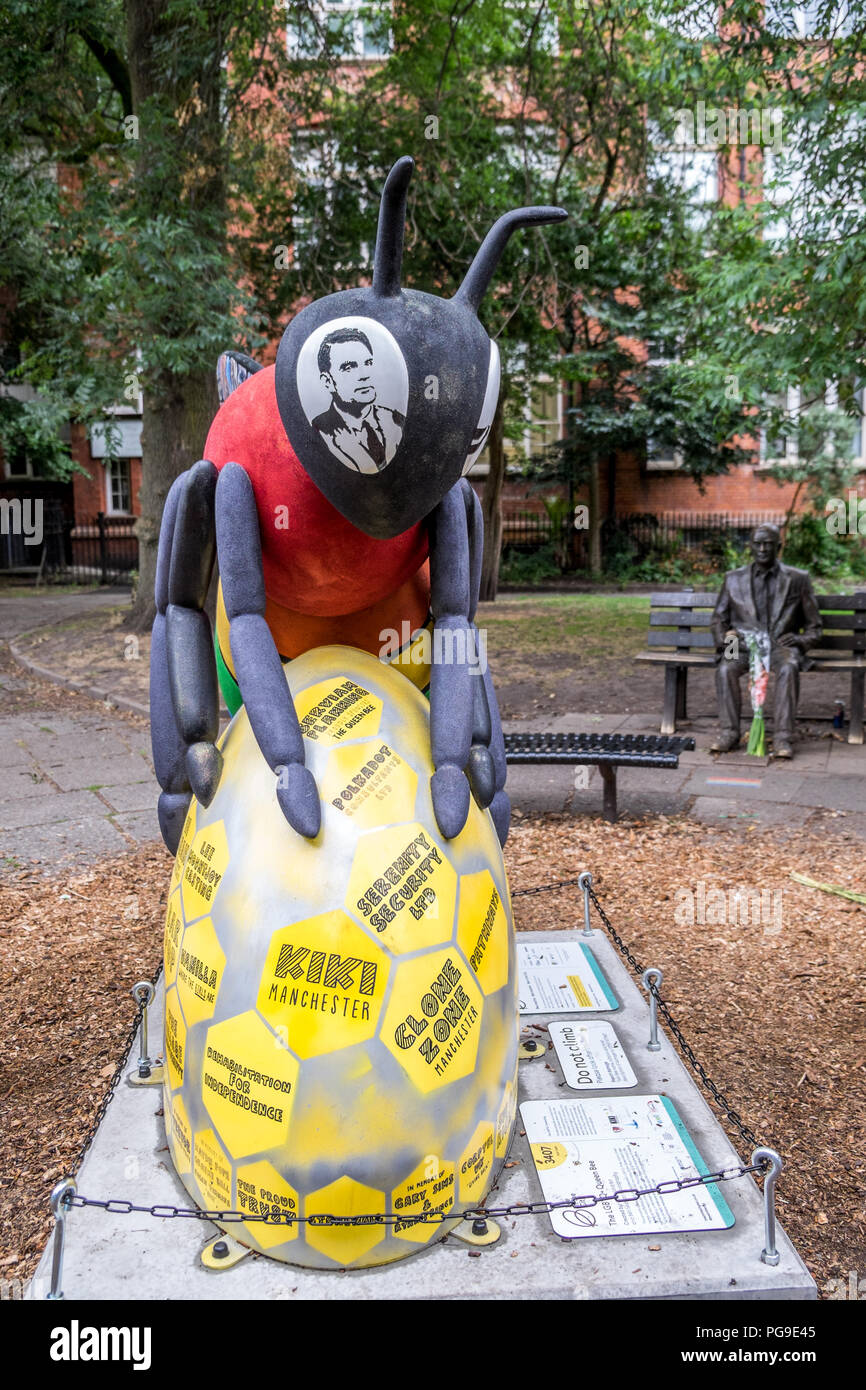 Manchester bee with the image of Alan Turing in the Bee,s eye with a statue of Alan Turing behind the Bee. Stock Photo