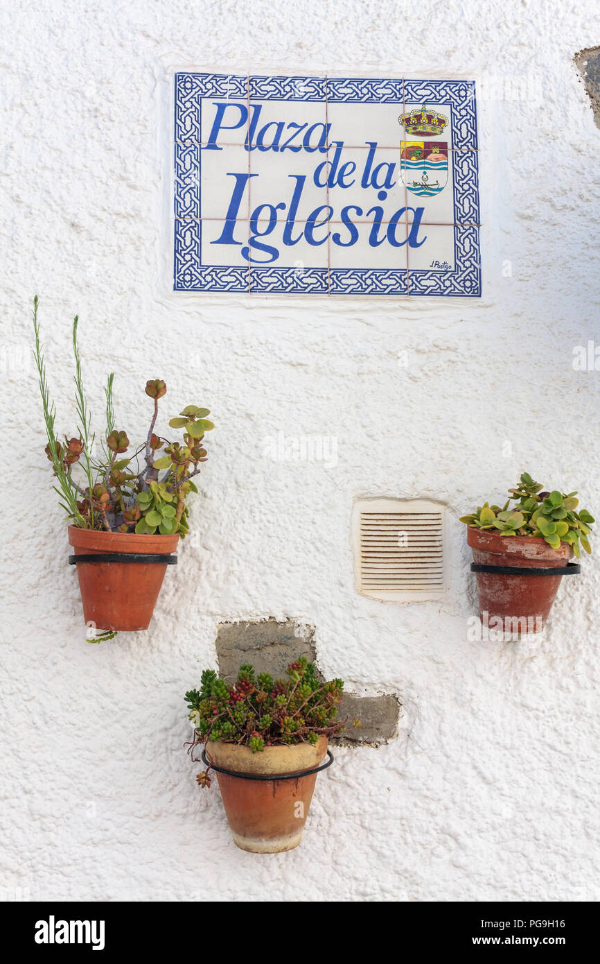 Flower pots against a white wall with a street name sign, Benagalbon, Spain Stock Photo