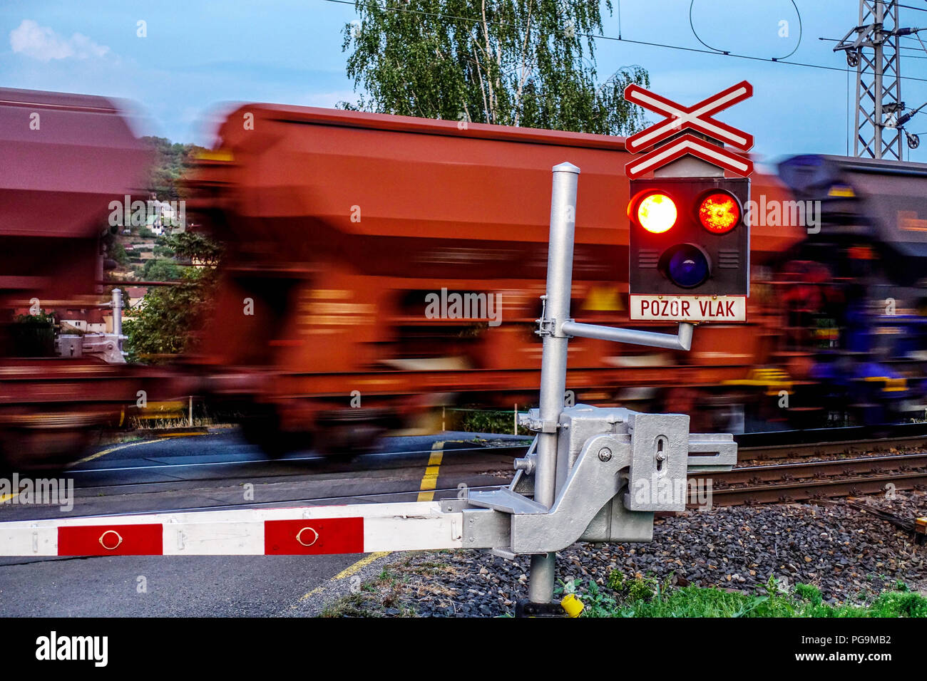 Cargo train passing a railroad crossing with red traffic lights flashing, Czech Republic, Europe Stock Photo