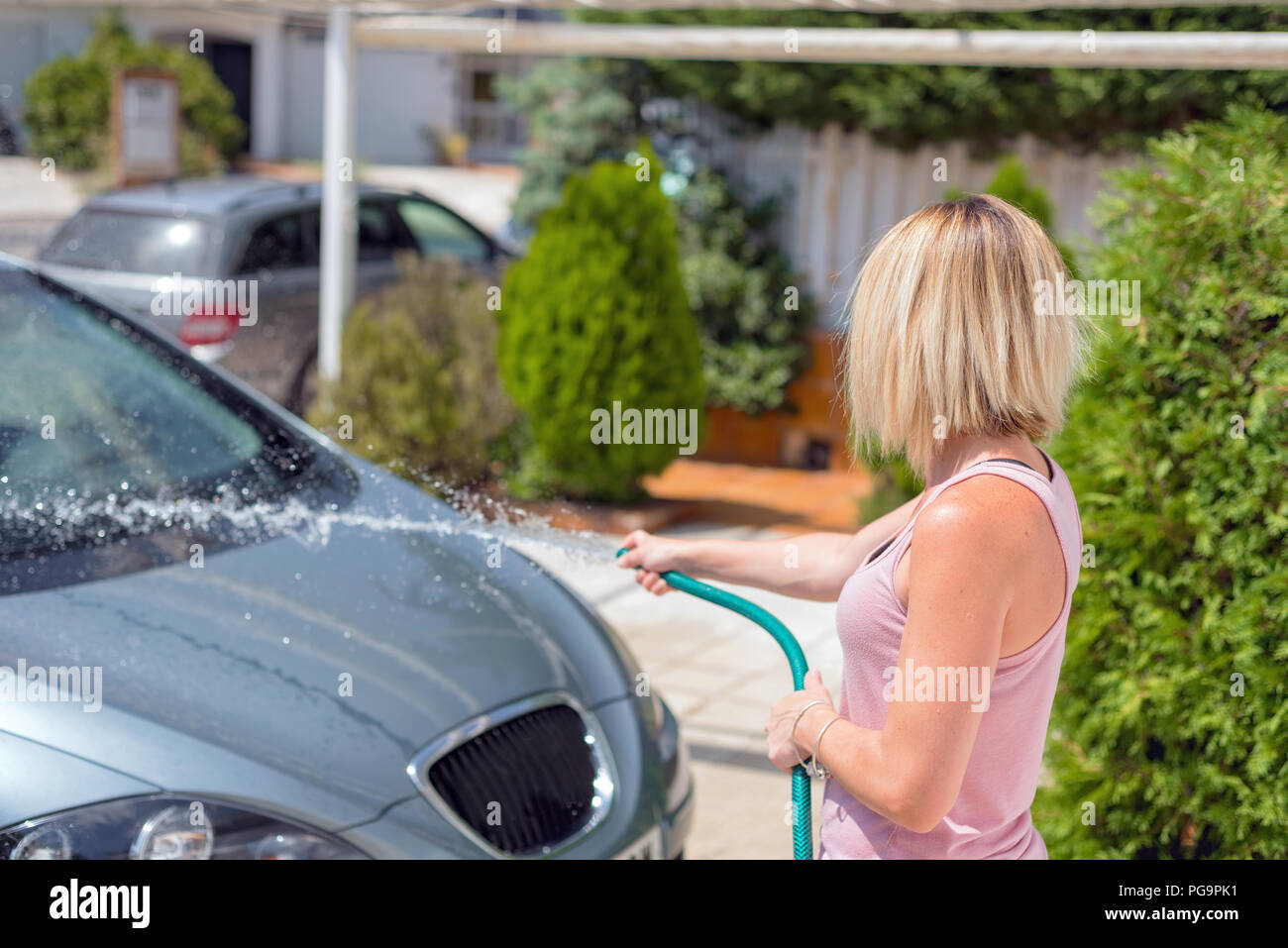 Young woman washing car with hose. Car detailing Stock Photo Alamy