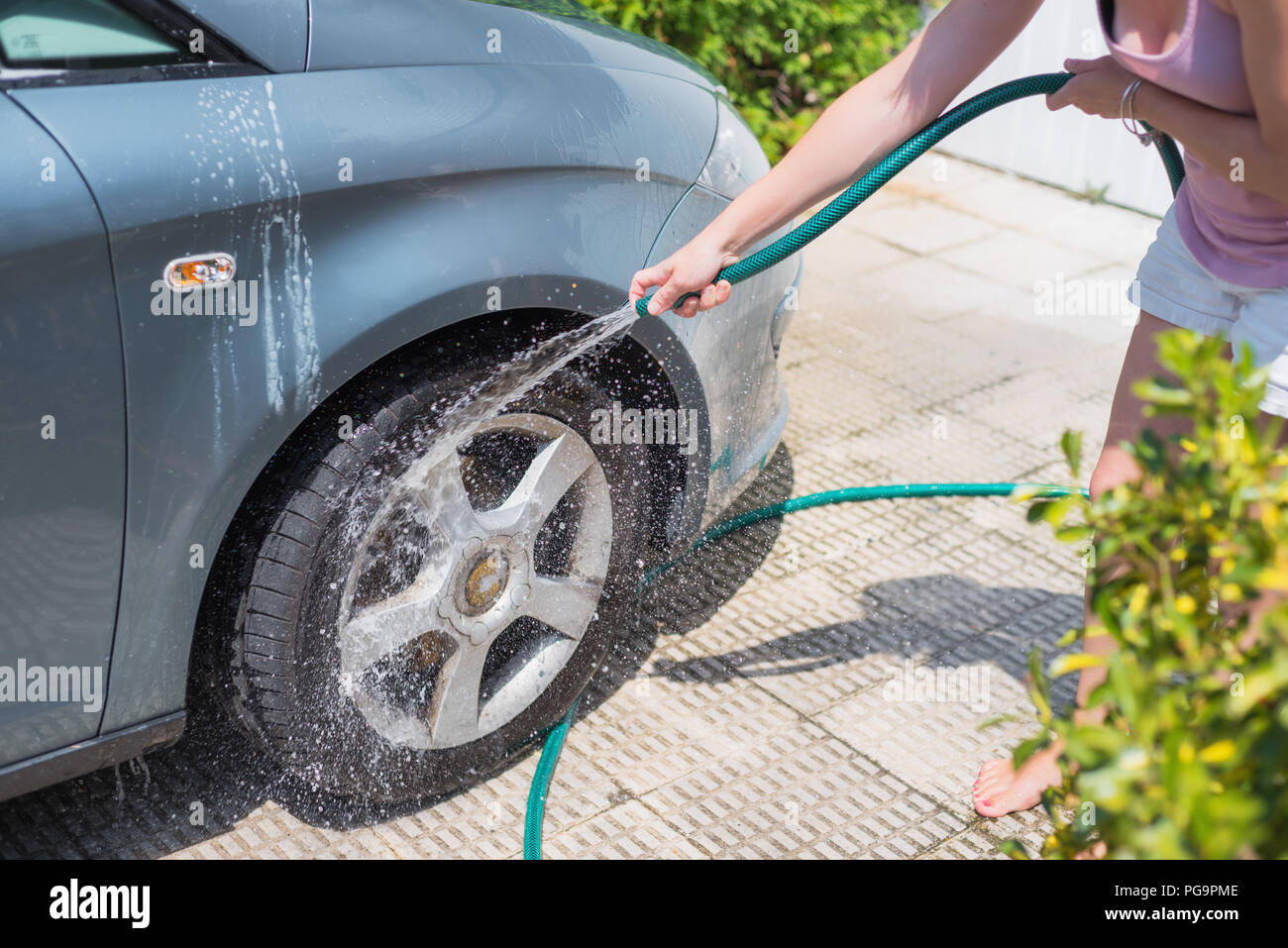 Young woman washing car with hose. Car detailing Stock Photo Alamy