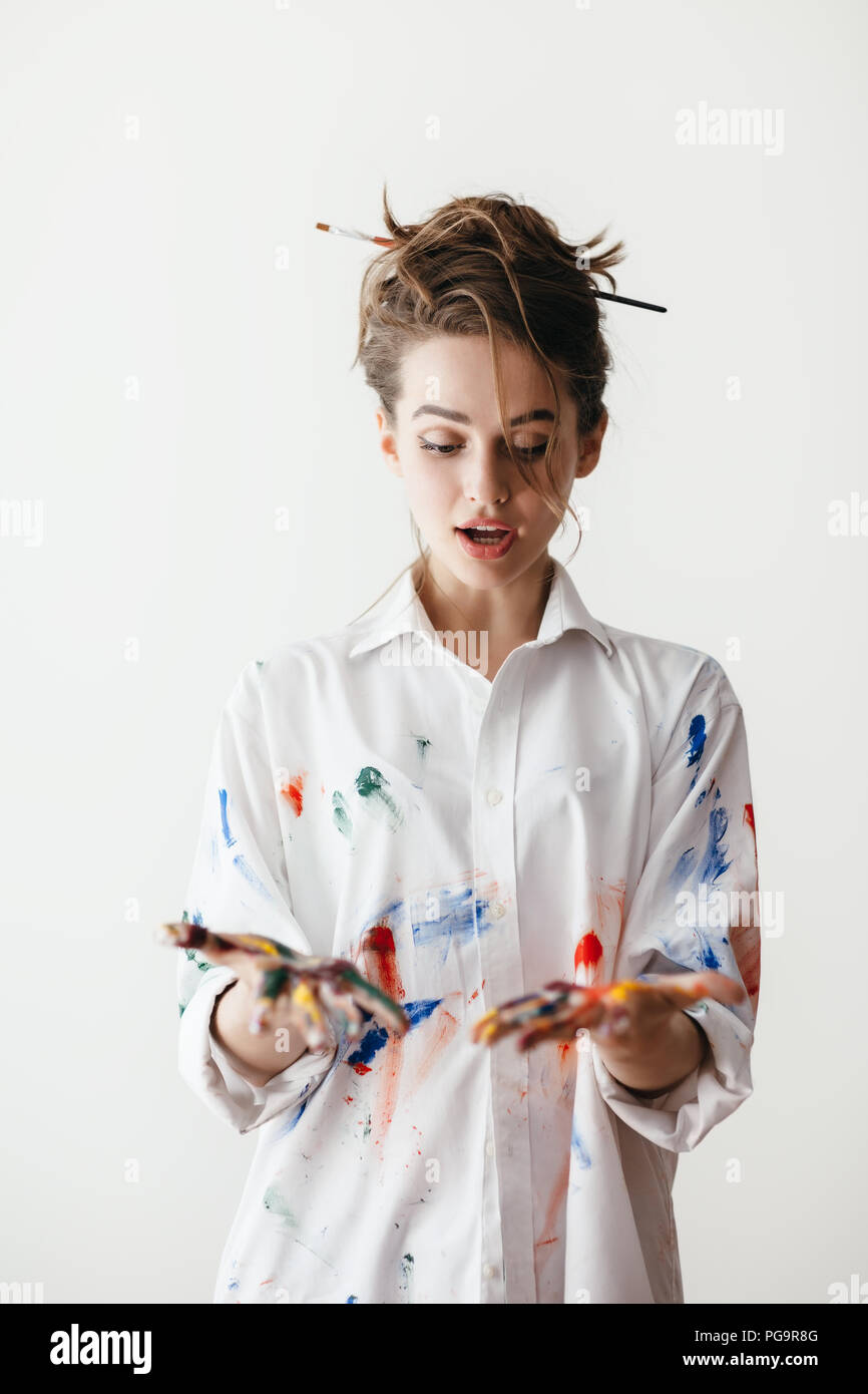 Portrait of young beautiful woman shocking with her hands dirty in multicolored paints. Working moment Stock Photo