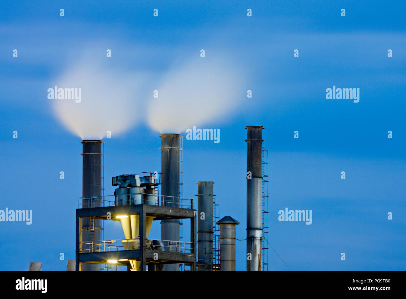 Smoke stacks of a chemical plant with night blue sky Stock Photo - Alamy