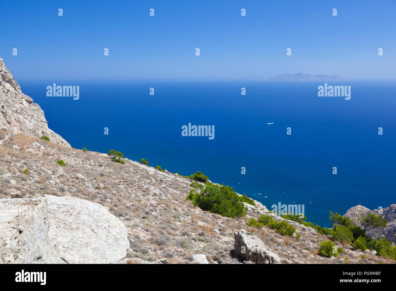 View from halfway up to the Profitis Ilias to the island Anafi with an airplane targeting the airport of Santorini far down. Stock Photo