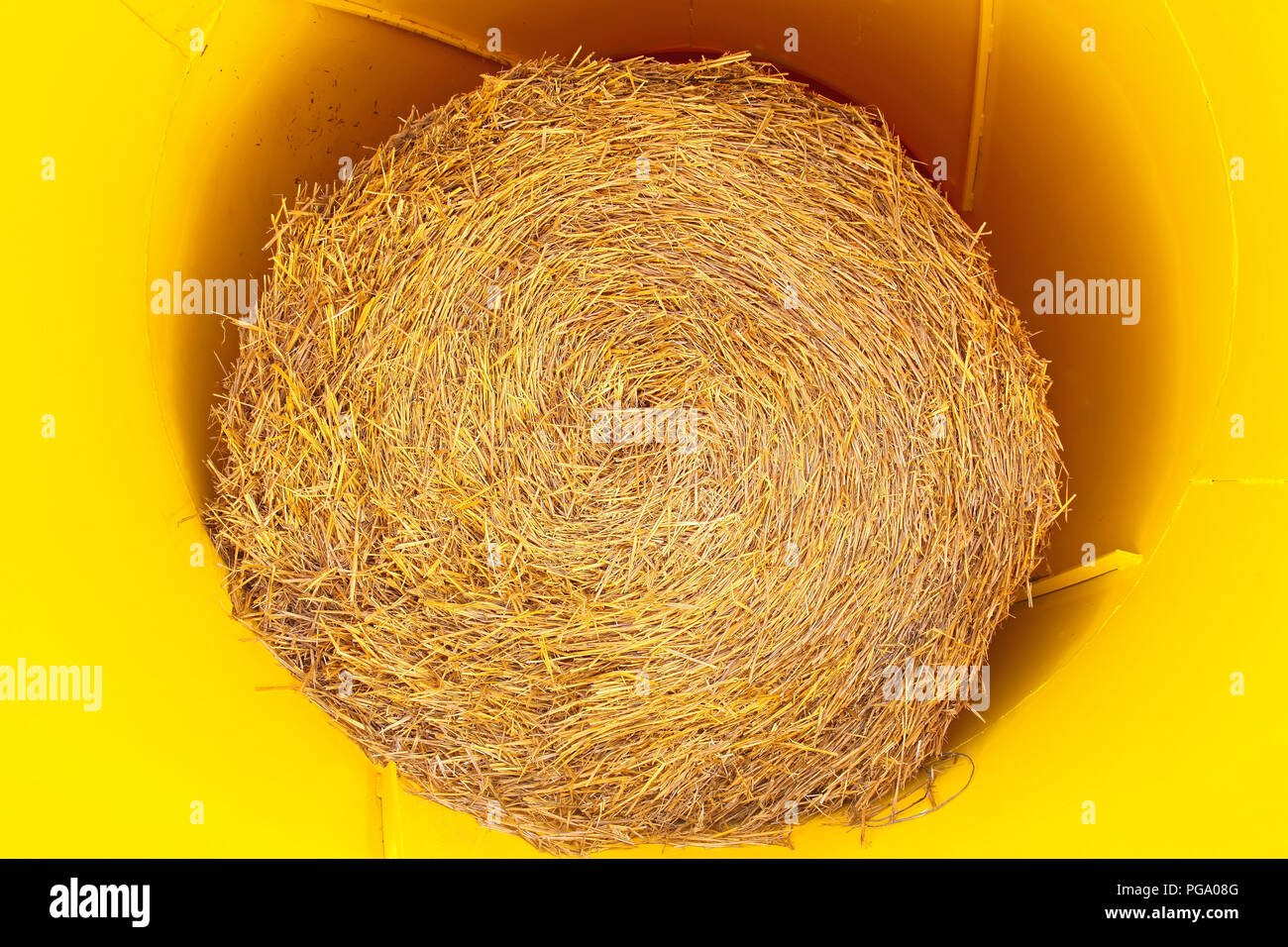 Straw bale roll in yellow rolling machine Stock Photo Alamy