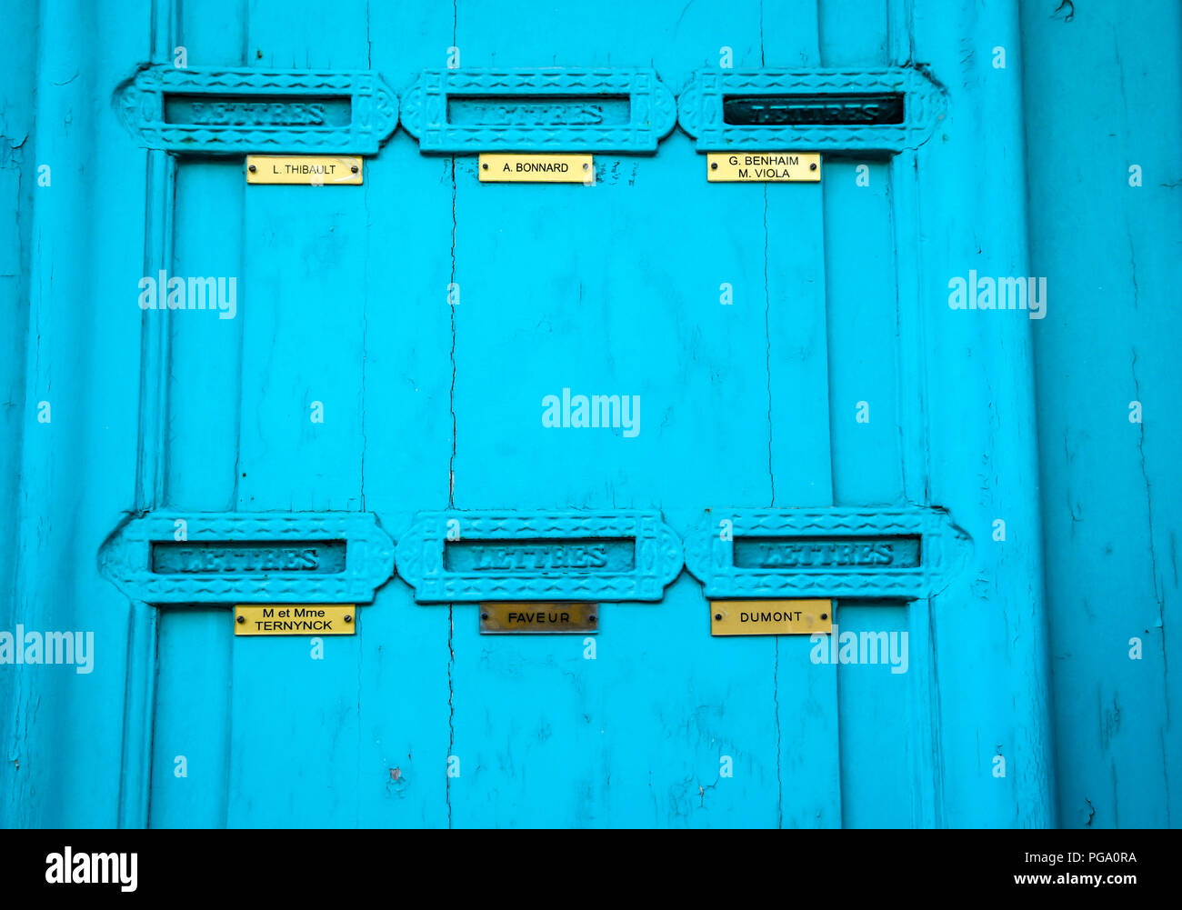 Bright Blue doors with Letter box flaps with nameplates in brass in an old apartment building in Lille, France Stock Photo