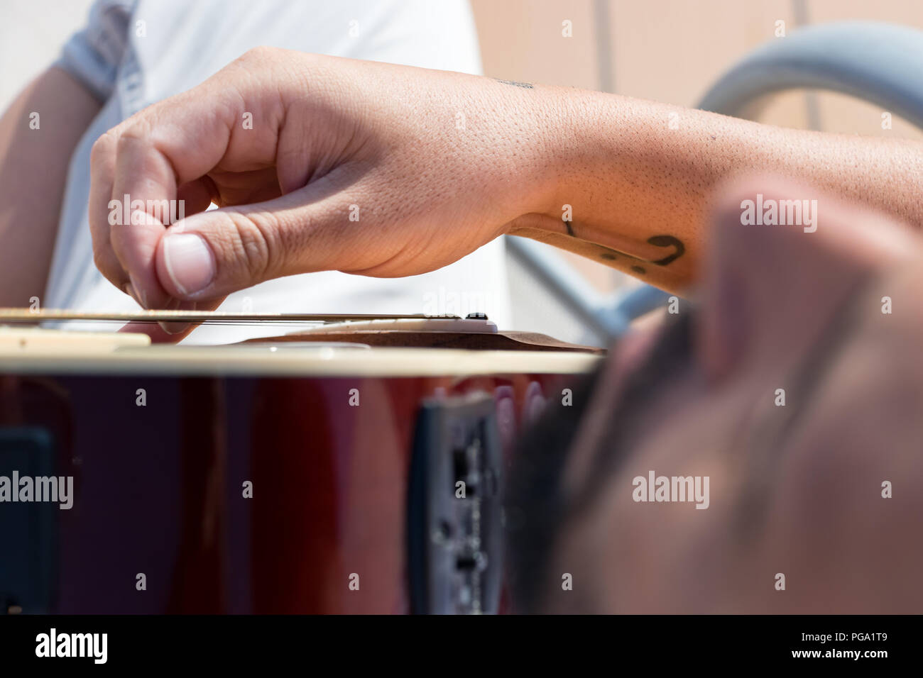 Close up of the right hand of a guitarist playing licks  with an acustic guitar outdoors. Stock Photo