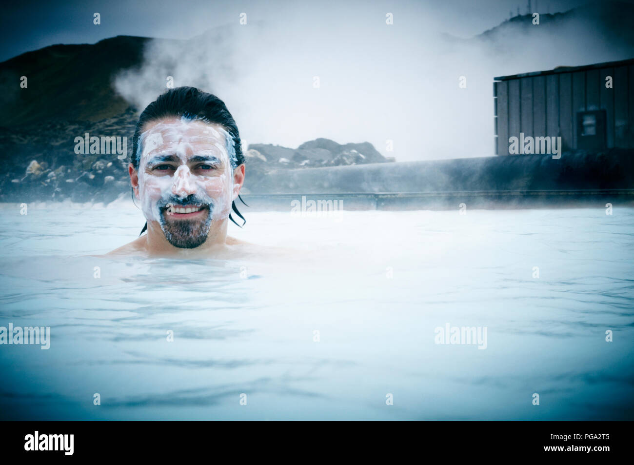 A man covered with a silica mud mask in the natural hot springs of the Blue  Lagoon, Iceland Stock Photo - Alamy