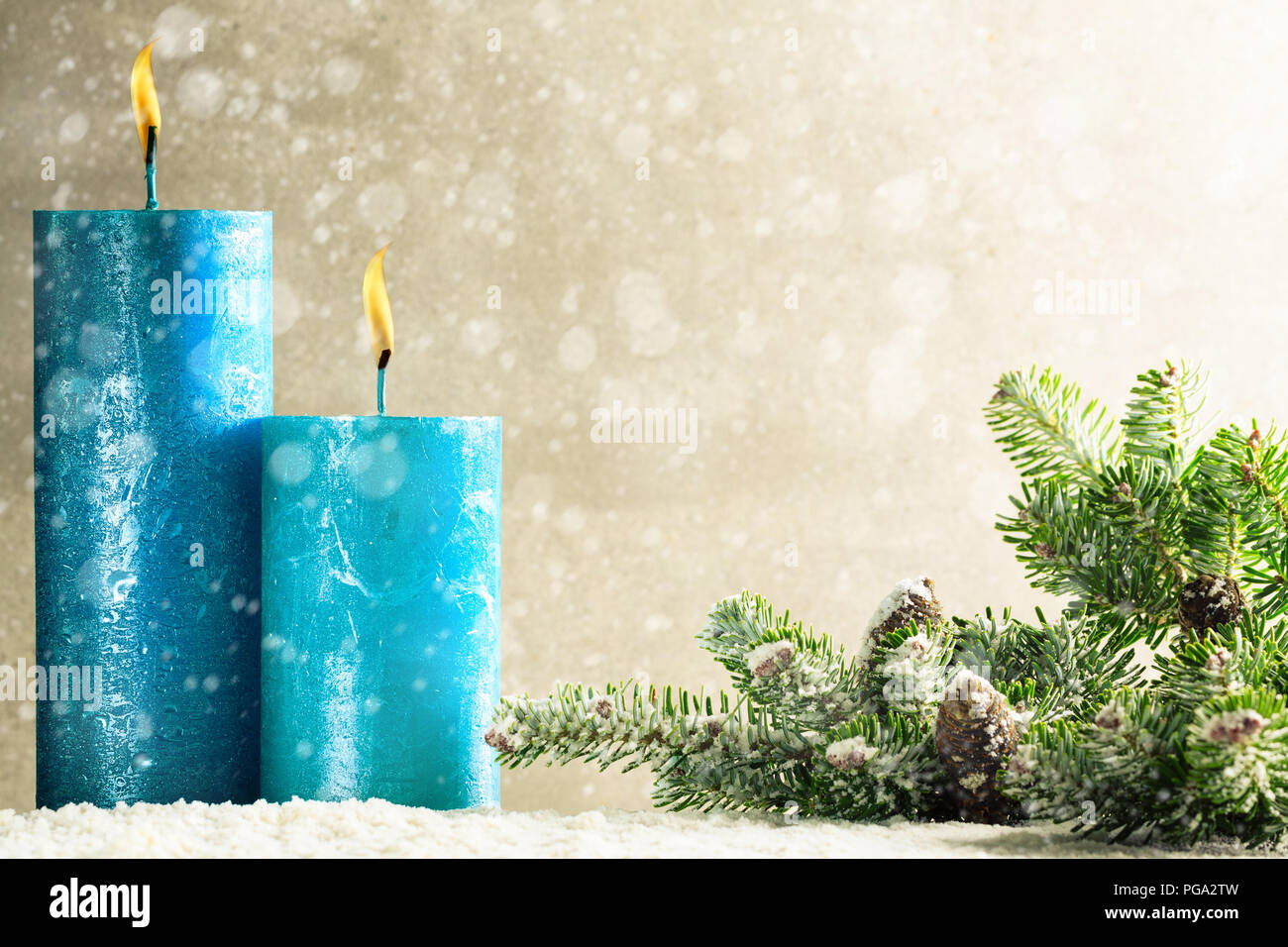 Christmas decoration with burned candles, spruce twig with cones and falling snow. Stock Photo