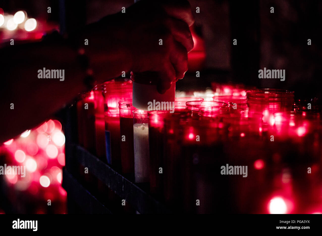 Religious offering, many red candles lit in a religious place Stock Photo