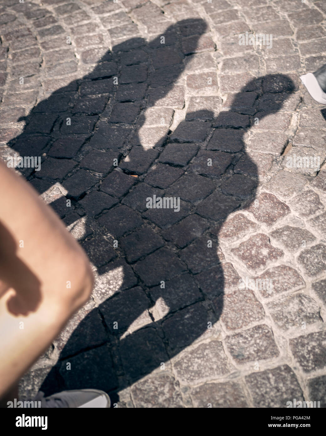 Shadow of two girls walking on a stone street Stock Photo