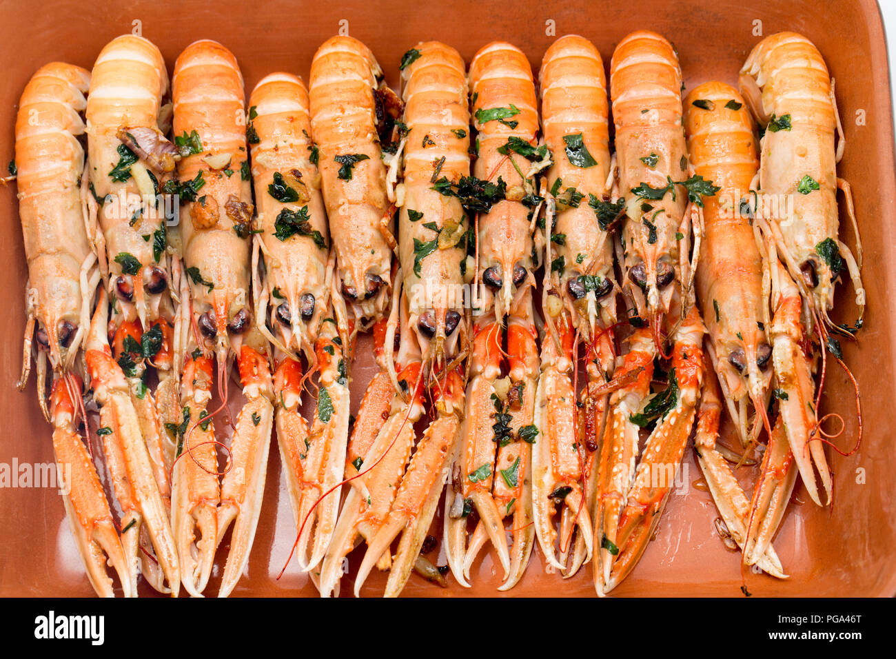 Scottish langoustines, Nephrops norvegicus, bought from a supermarket and photographed on a plate after frying in butter, garlic and parsley. The lang Stock Photo