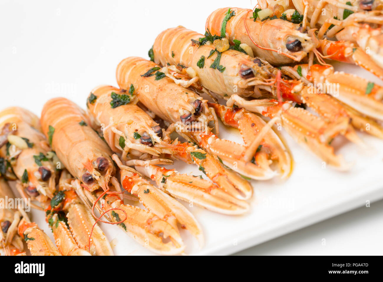 Scottish langoustines, Nephrops norvegicus, bought from a supermarket and photographed on a plate after frying in butter, garlic and parsley. The lang Stock Photo