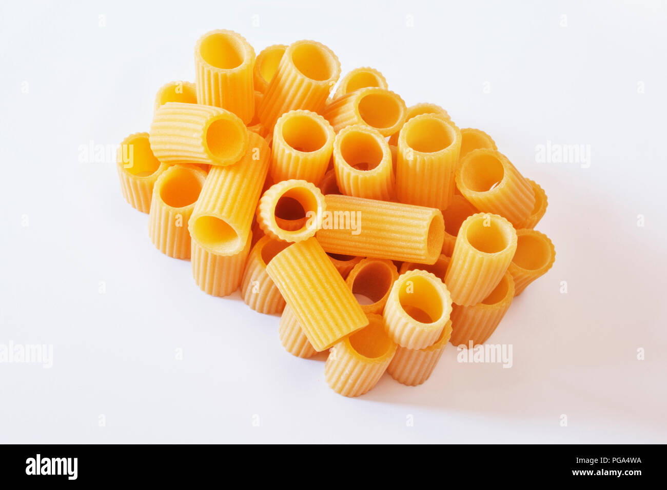 Italian pasta called mezzi rigatoni on a  white background ,tube-shaped pasta with ridges down their lenght , studio shot , Stock Photo
