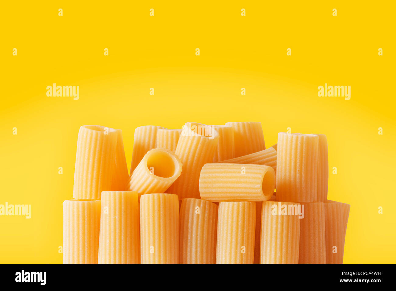 Italian pasta called rigatoni on a colored background ,tube-shaped pasta with ridges down their lenght , studio shot , Stock Photo