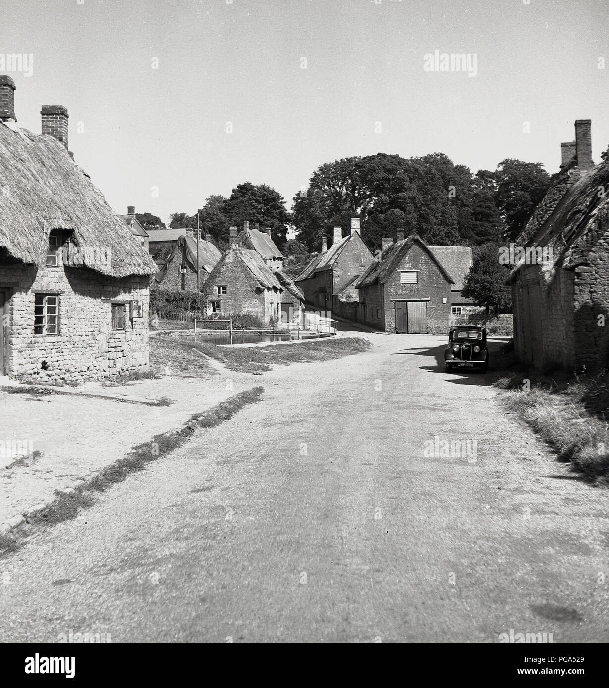1950s, the quiet rural English village of Wroxton, Oxfordshire, showing old buildings including thatched cottages. For such a tiny village, Wroxton has a rich history and its beauty and uniqueness lies in the fact that it has remained unchanged over the centuries. It has an abbey and duck pond. Stock Photo