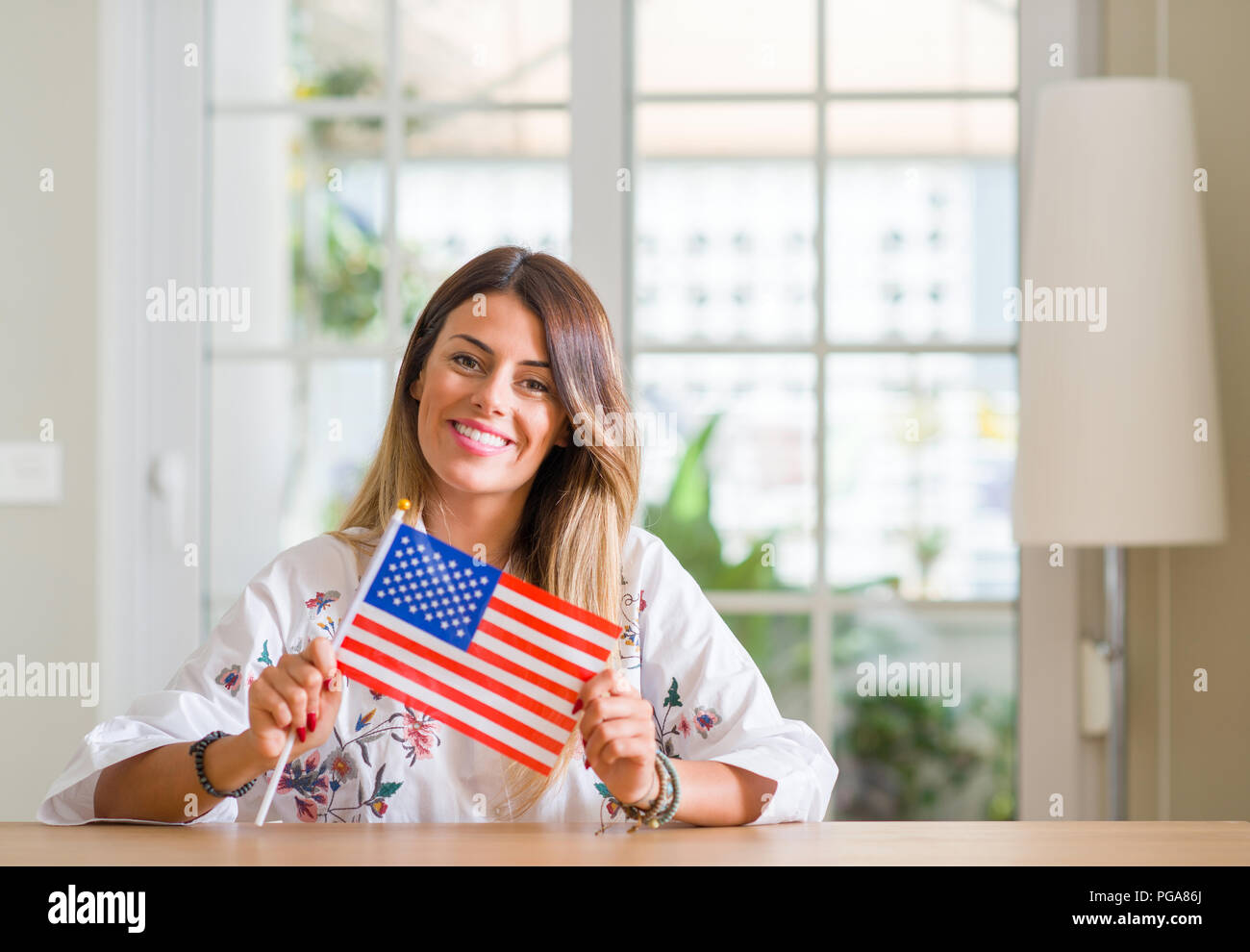 Young woman at home holding flag of united states of america with a ...