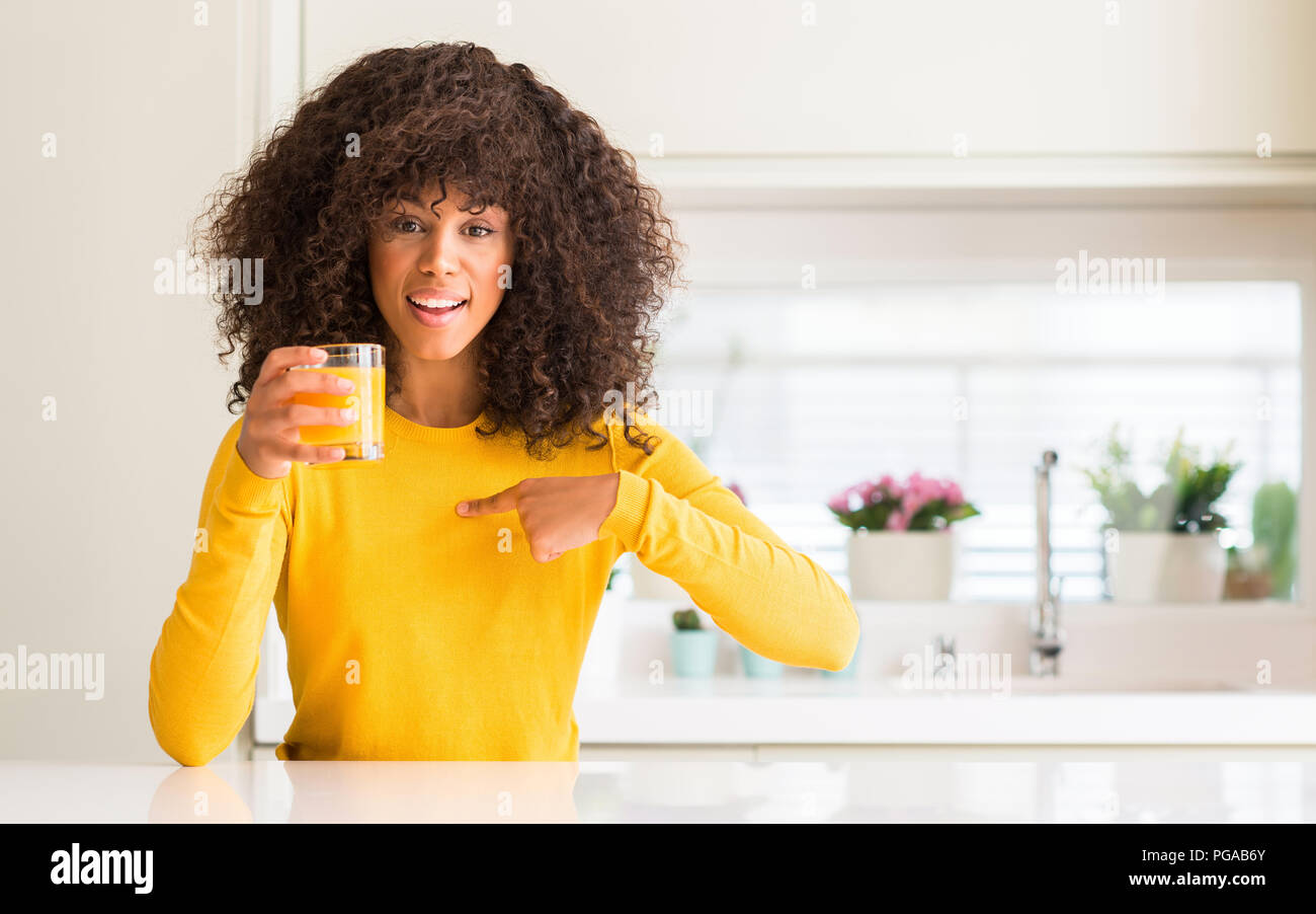 African american woman drinking orange juice in a glass with surprise ...